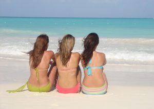Three women facing the sea, showing just their backs and hair